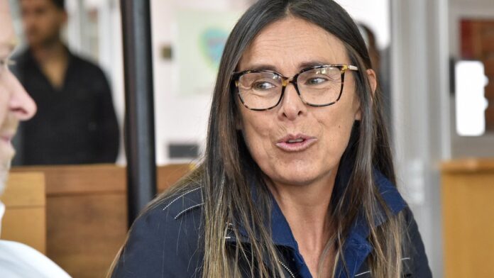 Dois tenistas se cumprimentam na rede após partida em quadra de saibro sob luz solar.