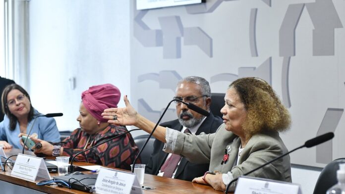 hemopa-destaca-inclus-o-de-profissionais-autistas- Profissional autista trabalha em ambiente de escritório, utilizando computador e documentos em mesa organizada.