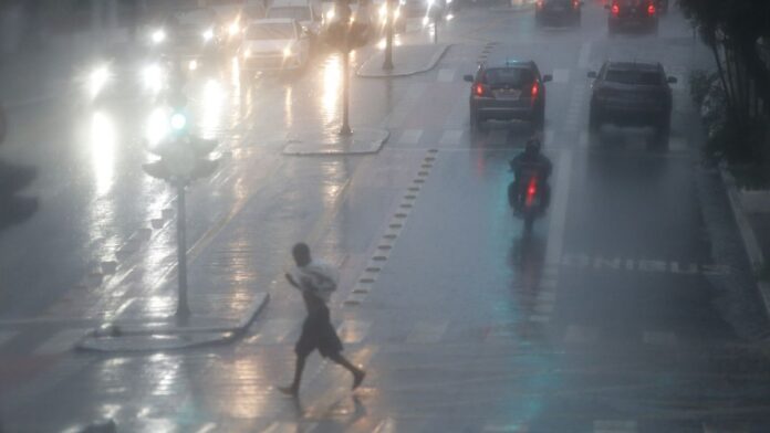 Imagem de satélite em tons de cinza mostrando nuvens espirais densas sobre o oceano, indicando formação de tempestade.