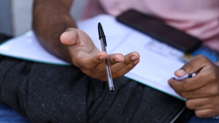 Estudante sentado em frente a um computador, com expressão concentrada, preenchendo formulário online do Enem.