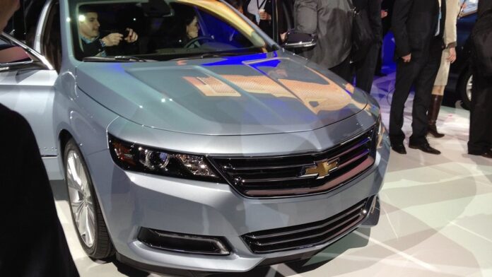 Dois veículos Kia, um SUV moderno e um carro elétrico compacto, exibidos em um estande iluminado de feira automotiva.