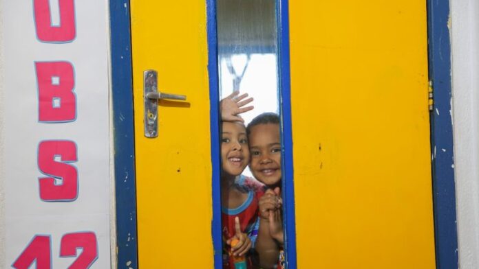 Crianças brincando em uma sala de aula colorida e iluminada de uma creche escolar.