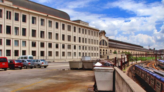 linhas-8-diamante-e-9-esmeralda-de-trens-t-m-opera Vista da plataforma de uma estação de trem vazia com trilhos e fiação aérea ao fundo sob céu nublado.