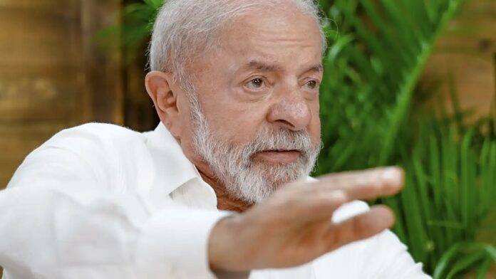 Presidente Lula gesticula durante pronunciamento em gabinete, com logo da Petrobras ao fundo.