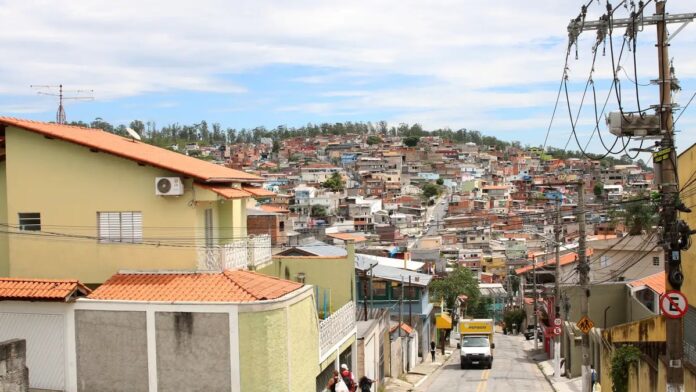 Grupo de moradores de Perus protesta segurando cartazes e faixas em frente a prédio público durante audiência.