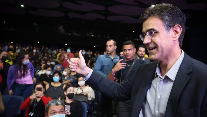 Fachada de um motel com letreiro luminoso, exibindo portão de entrada e arquitetura urbana típica à noite.