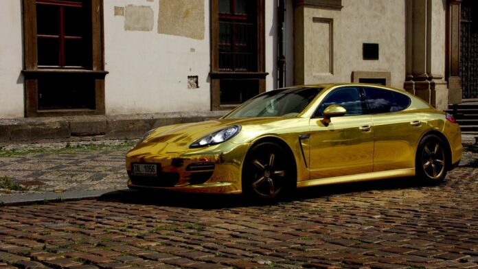 motorista-de-porsche-embriagado-atinge-fiat-siena- Carro esportivo de luxo prateado colidido contra um sedan popular em uma via urbana, com destroços espalhados no asfalto.