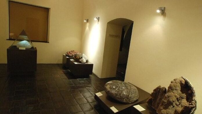 Pessoas em roda participam de oficina cultural com elementos de artesanato indígena em ambiente de museu.