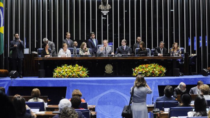 Nova governadora do Pará durante cerimônia oficial de posse, discursando em frente a uma bandeira do estado.