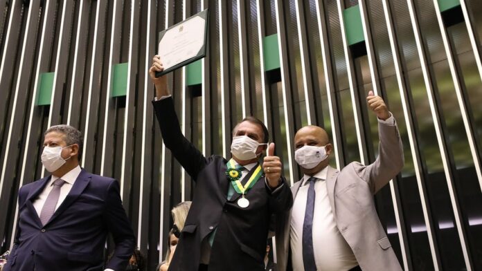 Plenário da Câmara dos Deputados com parlamentares discutindo documentos e votações, focando no ambiente legislativo.