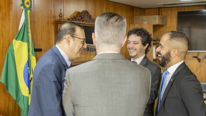 Marcelo Weick, homem de meia-idade, sorridente, vestindo terno e gravata, em estúdio com fundo neutro.