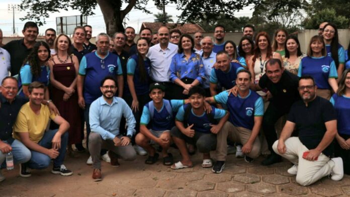 Engenheiros e autoridades vestindo coletes refletivos avaliam canteiro de obras de infraestrutura em terreno ensolarado.