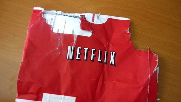 Pessoa sentada no sofá segurando uma tigela de pipoca, assistindo a uma televisão em uma sala de estar aconchegante.