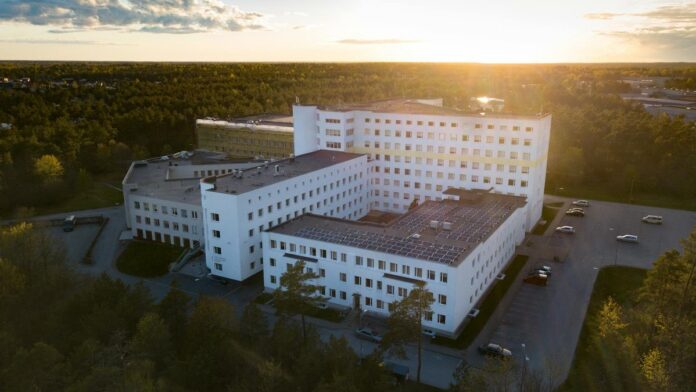 Aerial view of a modern hospital building surrounded by greenery at sunset, illustrating serene healthcare environment.