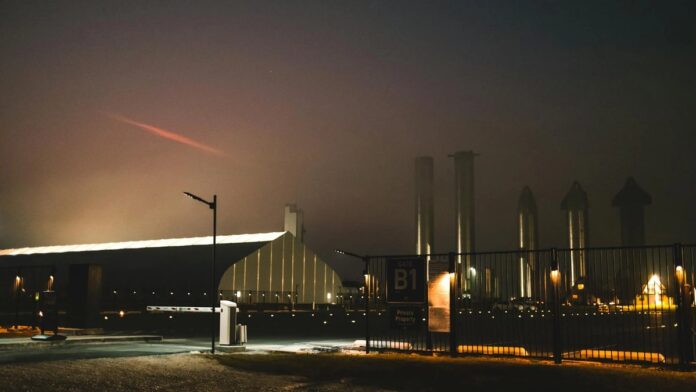 s4-08d49b9f8fcc-6 Dramatic night view of SpaceX facility with fog and lights in Brownsville, Texas.