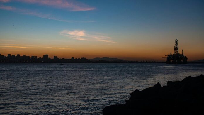 Silhouette of an oil rig against a vibrant sunset over the waters of Rio de Janeiro, Brazil.