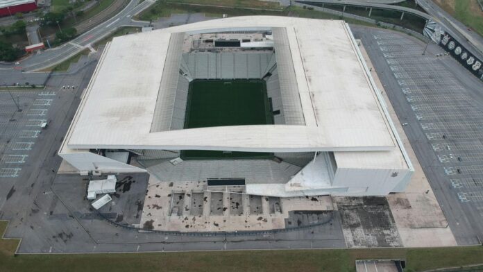 High-angle shot of a contemporary stadium from above, surrounded by parking and roads.