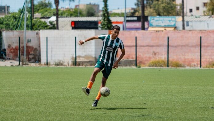 A soccer player kicks the ball on the field.
