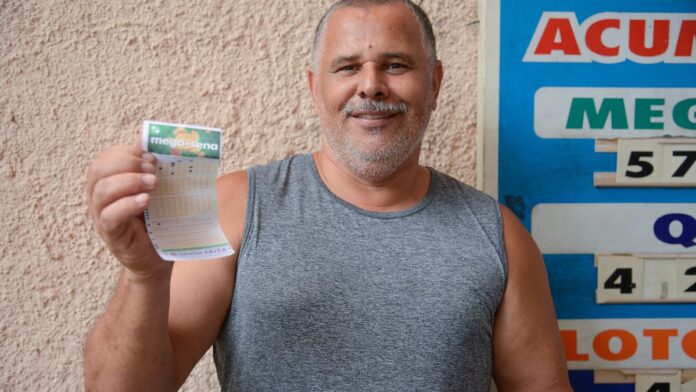 Rio de Janeiro (RJ), 23/12/2023 - O militar Luiz Cláudio Viana com o volante da aposta da Mega-Sena da Virada em uma casa lot