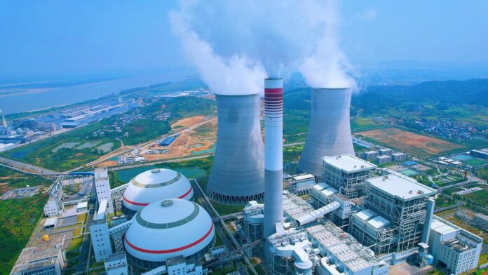 s4-1ea6d7371448 Aerial shot of a power plant with cooling towers emitting steam in Jiujiang, China.