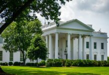 Trump ameaça atacar Irã em caso de descumprimento do acordo de cessar-fogo The White House framed by trees and greenery, in Washington, D.C., under a bright sky.
