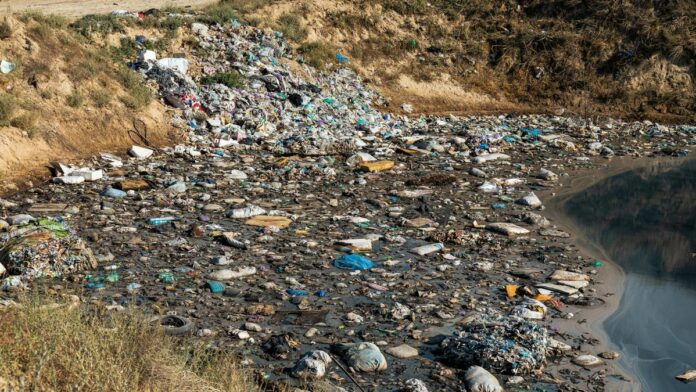 Plastic waste and debris polluting a riverbank, highlighting environmental challenges.