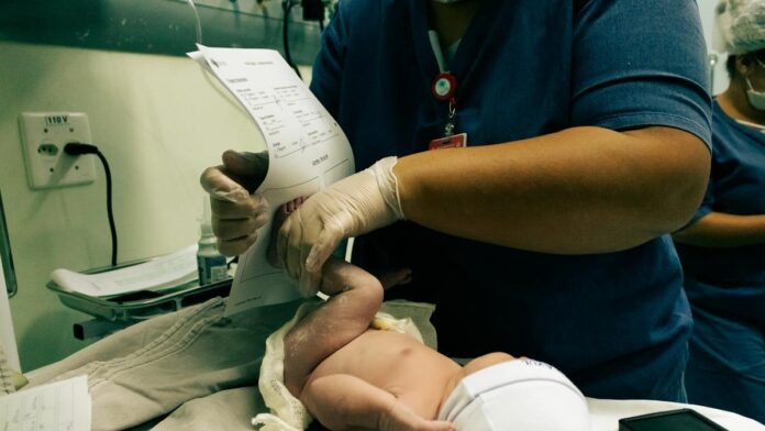 Healthcare professional handling a newborn in São Paulo hospital, ensuring crucial initial care.