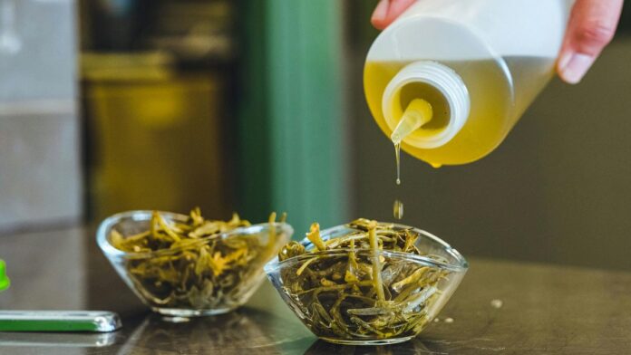 Pouring olive oil over fresh herbs in glass bowls, adding flavor to the dish.