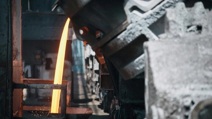 A powerful image of molten metal pouring in a heavy industry steel mill setting.