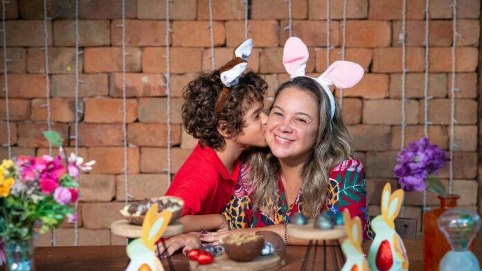 Mother and son celebrating Easter with bunny ears and colorful decorations, sharing a loving moment.