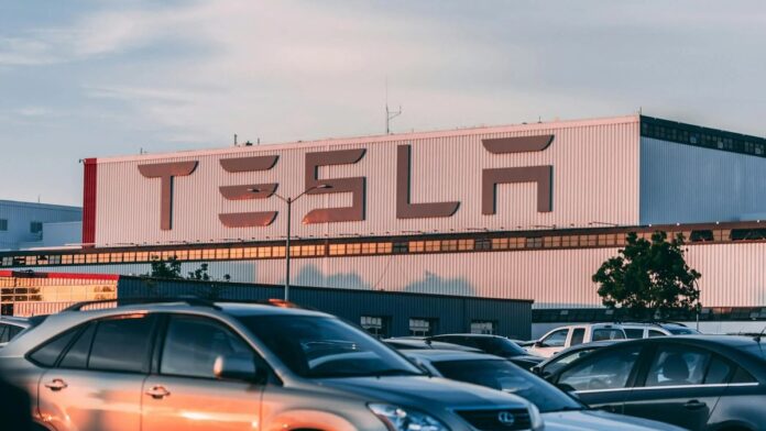 Tesla factory with parked cars during sunset, showcasing modern automotive industry vibes.