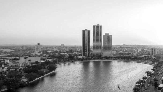 Stunning aerial cityscape of Campina Grande, Brazil in black and white showcasing tall buildings and a tranquil lake.