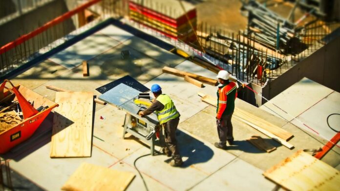 Construction workers engaging in tasks at an outdoor building site with safety hats and equipment.