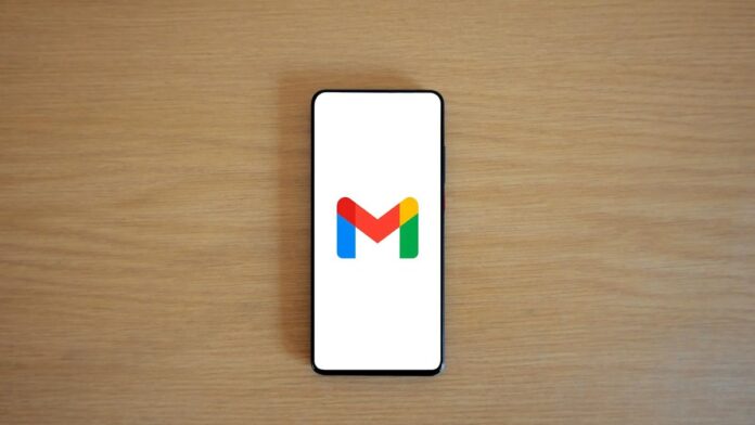 A smartphone displaying the Gmail app logo on a wooden surface, viewed from above.