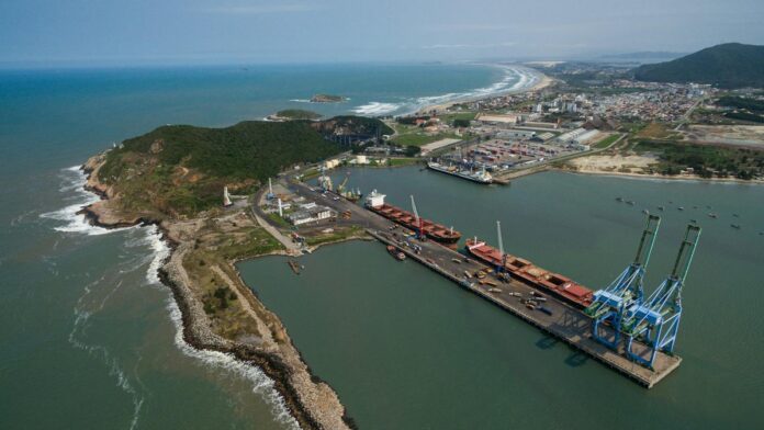 Aerial shot of Imbituba port showing docks, cranes, and coastline in Brazil.
