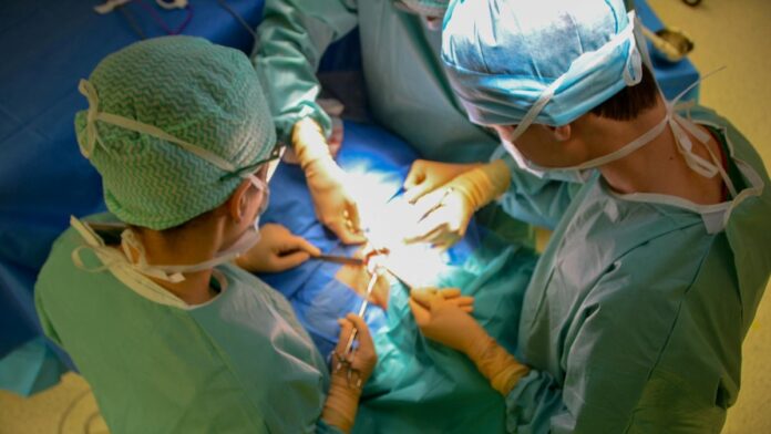 Surgeons in sterile attire performing surgery with precision in a hospital operating room.