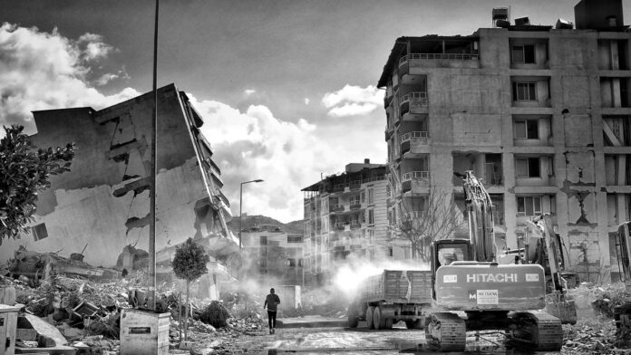 A powerful image of urban devastation after an earthquake, showing collapsed buildings and excavation equipment.
