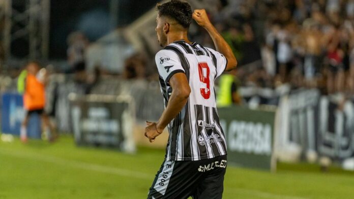 Football player in black-and-white jersey celebrates goal on field.