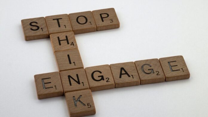 Wooden Scrabble tiles spelling 'Stop Think Engage' for strategic concepts.