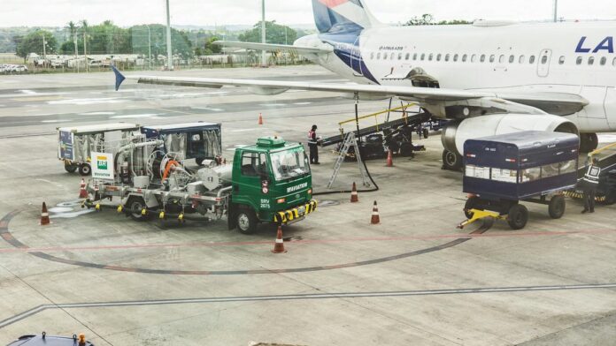 Ground support services in action at an airport terminal with visible aircraft and service vehicles.
