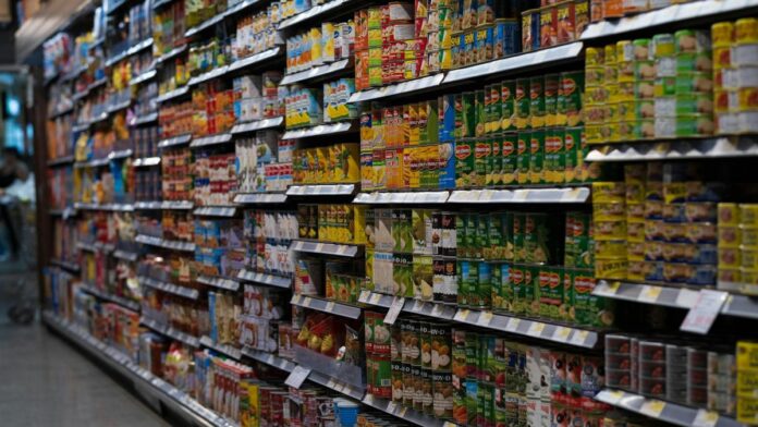 A supermarket aisle filled with various canned goods on shelves, showcasing retail diversity.