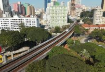 Governo de SP libera R$ 300 milhões para financiar obras em municípios paulistas Aerial view of São Paulo cityscape with metro line and greenery during daytime.