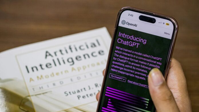 Close-up of a smartphone displaying ChatGPT app held over AI textbook.