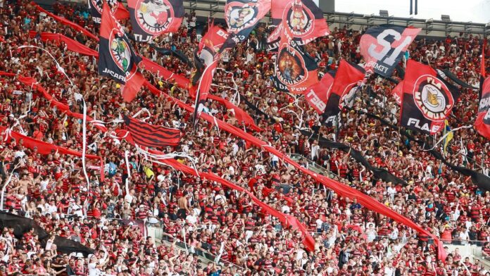 Energetic crowd of Flamengo supporters waving flags in Maracanã Stadium, Rio de Janeiro.