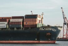 HD Hyundai inova com construção de navios em metades; técnica desafia setor naval brasileiro Cargo ship with containers and cranes in Hamburg port.