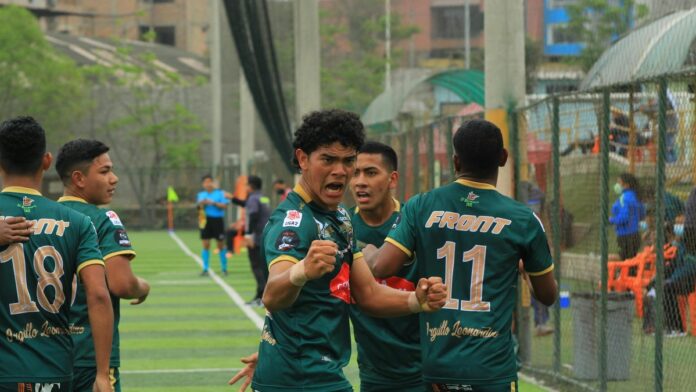 Group of young football players celebrating a successful play during a match.