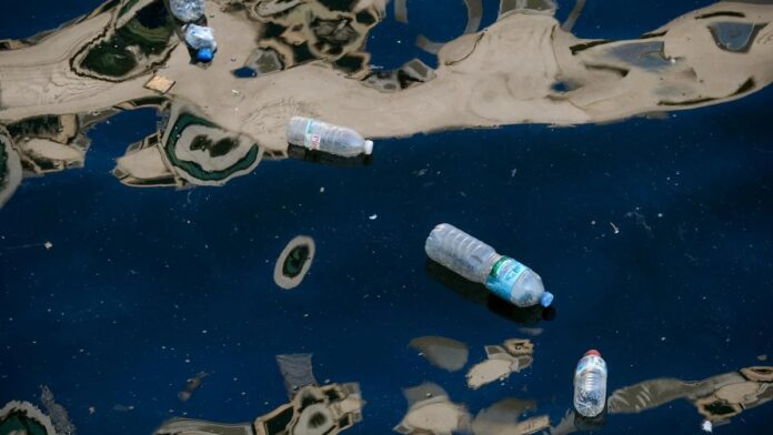 s4-a8b0ebc48774-1 Plastic bottles floating in dark polluted water illustrating environmental pollution.