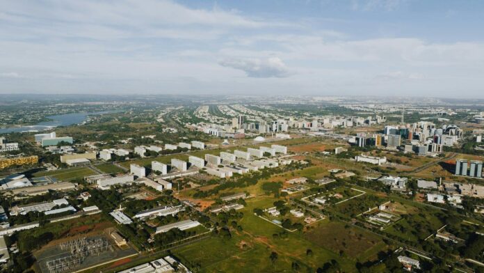 Aerial shot of Brasília showcasing its urban landscape, buildings, and greenery in daylight.