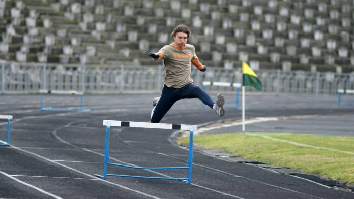 Athlete demonstrating speed and agility while jumping hurdles during track event.