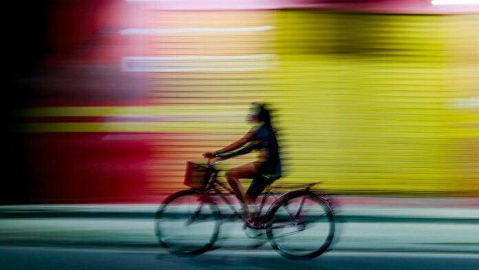 Dynamic motion blur of a person cycling past colorful shutters at night in Parintins, Amazonas, Brazil.